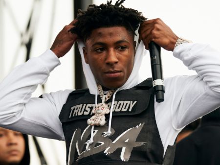 NBA YoungBoy putting on the hood of the jacket he's wearing.